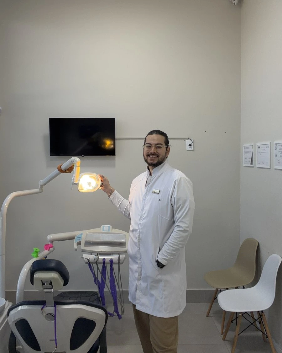 Dr. Artur Hirai no consultório, ajustando o refletor da cadeira odontológica