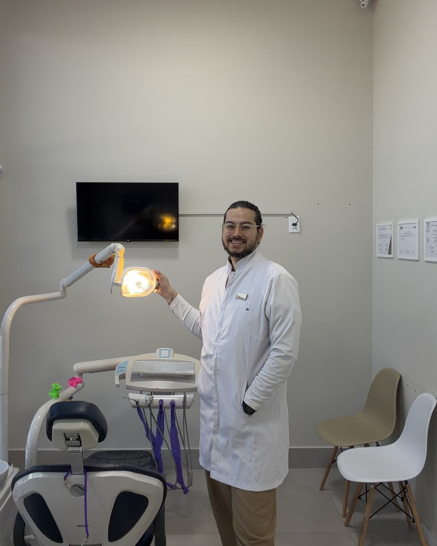 Dr. Artur Hirai no consultório, ajustando o refletor da cadeira odontológica